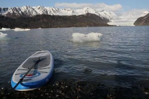 paddleboard in water with snowy mountains in background